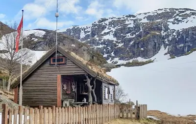 a small wooden house with a mountain in the background at 4 Bedroom Nice Home In Etne in Etnesjøen