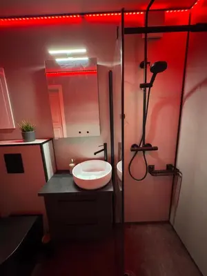 a bathroom with a sink and a shower with red lights at Moderne og sentral leilighet med koselig og privat uteplass! in Hornnes