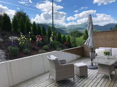 a patio with a table and chairs and an umbrella at Moderne og sentral leilighet med koselig og privat uteplass! in Hornnes