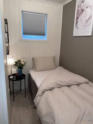 a bedroom with two beds and a table with a window at Moderne og sentral leilighet med koselig og privat uteplass! in Hornnes