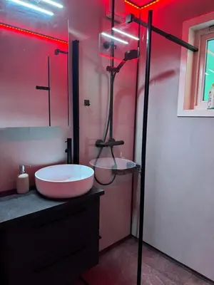 a bathroom with a sink and a shower with red lights at Moderne og sentral leilighet med koselig og privat uteplass! in Hornnes