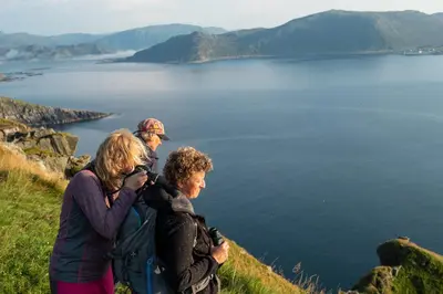a group of people standing on a hill overlooking a lake at Runde Miljøsenter & Opplev Runde in Runde