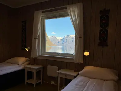 a room with two beds and a window with a view at Svingen Guesthouse - Panoramic Fjord Views in Flåm in Flåm