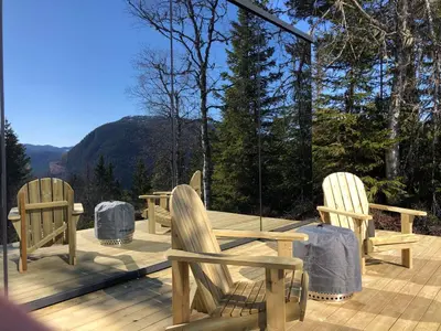 three wooden chairs and a table on a deck at Vidsyn Midjås in Vistad