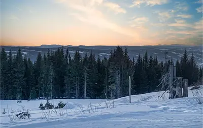 a snow covered hill with trees and the sunset in the background at Stunning Home In Øyer With Sauna in Øyer