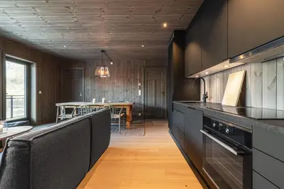 a kitchen with black cabinets and a table in the background at Mountain nest in Hemsedal close to the ski slopes in Hemsedal