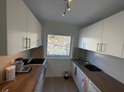 a kitchen with white cabinets and a window at Lovely 2 bedroom apartmen with free parking in Bergen