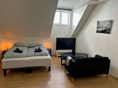 a bedroom with a bed and a flat screen tv at Marken Studio Apartments in Bergen