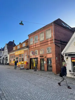 a man walking down a cobblestone street with buildings at Marken Studio Apartments in Bergen
