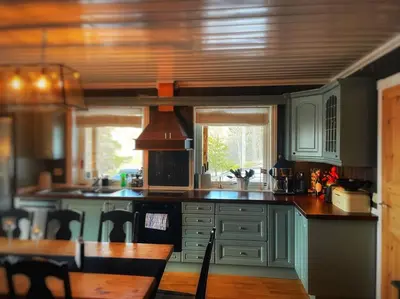 a kitchen with blue cabinets and a table with chairs at Stor hytte med 4 soverom og panoramautsikt over Tinnsjøen ved Rjukan og Gaustatoppen in Håkånes