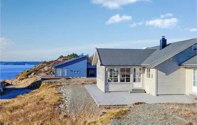 a house on the side of a hill next to the ocean at Gorgeous Home In Sveio With Wifi in Sveio