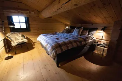 a bedroom in a log cabin with a bed and a chair at Roalden Mountain Lodge in Stranda