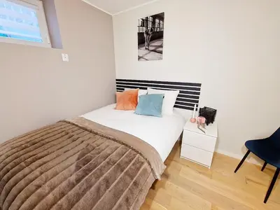 a small bedroom with a bed and a chair at Ibsens apartaments in Bergen