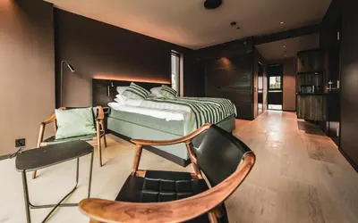 a bedroom with a bed and a chair at Elva Hotel in Vossevangen