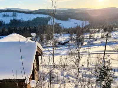 a snow covered hill with a house in the foreground at 6 person holiday home in HURDAL-By Traum in Hurdal