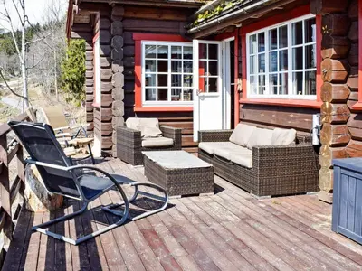 a porch with a rocking chair and chairs on a cabin at 6 person holiday home in HURDAL-By Traum in Hurdal
