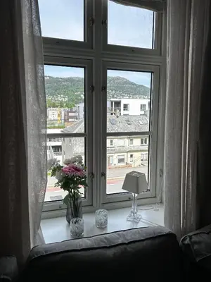 a window with flowers on a table next to a couch at Modern Apartment in the center of Bergen in Bergen
