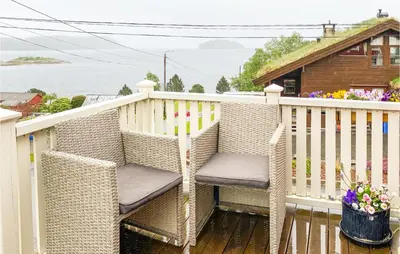 a porch with a wicker chair on a white fence at Stunning Home In Ålesund With Kitchen in Ålesund
