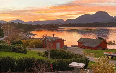 a house on the shore of a lake at sunset at Stunning Home In Ålesund With Kitchen in Ålesund