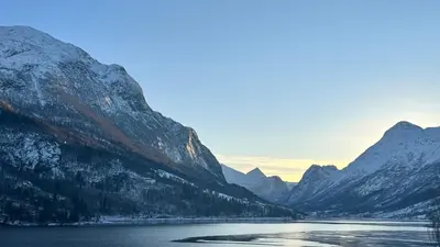 a lake in front of mountains with snow on them at Solvik #apartment #Loen in Loen
