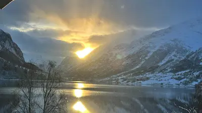 a sunset over a river with snow covered mountains at Solvik #apartment #Loen in Loen