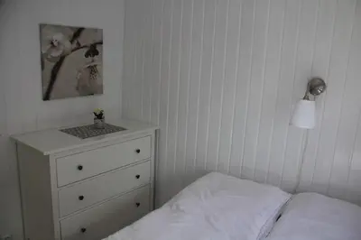 a bedroom with a bed and a dresser and a lamp at Rosendal Hyttetun in Rosendal
