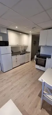 a large kitchen with white appliances and wooden floors at Rosendal Apartments Motellet in Rosendal