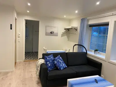 a living room with a black couch and a window at Rosendal Apartments Motellet in Rosendal