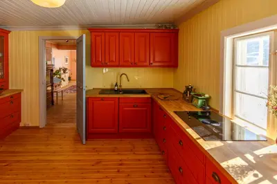 a kitchen with red cabinets and a sink at Vinjestogo- mesmerizing mountain view, sauna with a view and eco living in an old school house in Løken