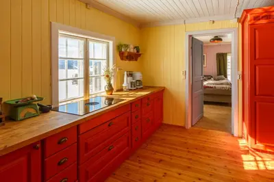 a kitchen with yellow walls and red cabinets and a window at Vinjestogo- mesmerizing mountain view, sauna with a view and eco living in an old school house in Løken