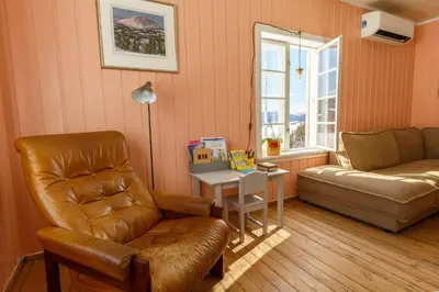 a living room with a couch and a chair and a table at Vinjestogo- mesmerizing mountain view, sauna with a view and eco living in an old school house in Løken