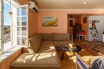 a living room with a couch and a table at Vinjestogo- mesmerizing mountain view, sauna with a view and eco living in an old school house in Løken