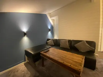 a living room with a black couch and a wooden table at Leilighet Sølendet, i Brekken ved Røros in Røros