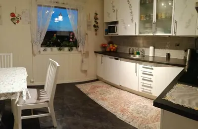 a kitchen with white cabinets and a table and a window at Gjesterom til leie i et privat hus in Brumunddalen
