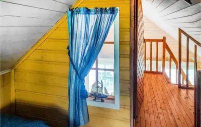 a blue curtain in a room with a window at Cozy Home In Mosvik With House Sea View in Mosvik