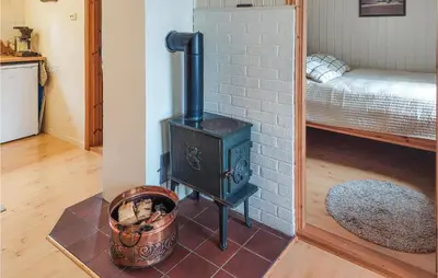 a wood stove in a room with a bed at Cozy Home In Mosvik With House Sea View in Mosvik