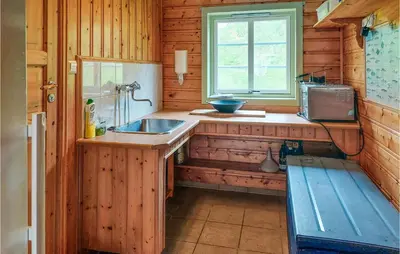 a kitchen with a sink and a window in a cabin at Cozy Home In Mosvik With House Sea View in Mosvik
