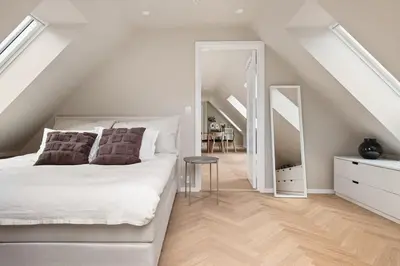a white bedroom with a bed and a staircase at Dinbnb Apartments I Mid-City Luxury with Mini Balcony and Smart TV & Sound System in Bergen