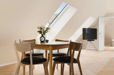 a dining room with a table and chairs and a tv at Dinbnb Apartments I Mid-City Luxury with Mini Balcony and Smart TV & Sound System in Bergen