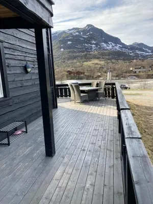 a wooden deck with a picnic table and a mountain at Lun og koselig hytte med sauna på Filefjell in Tyinkrysset