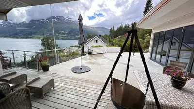 a porch with an umbrella and a view of a lake at Panorama #CasaSolvik #Loen in Loen