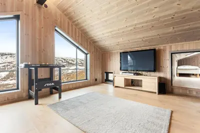 a living room with wooden walls and a flat screen tv at Rindabakkane Lodge in Sogndal