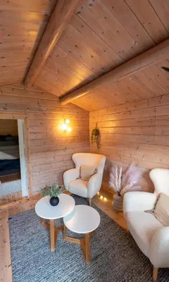 a room with two chairs and tables in a cabin at Cabin near the lake in Årset