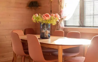 a dining room table with pink chairs and a vase of flowers at Cabin near the lake in Årset