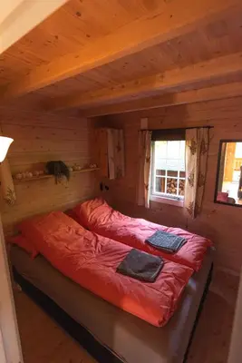 a bed in a log cabin with a window at Cabin near the lake in Årset