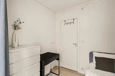 a white bedroom with a bed and a vase with flowers at Family Friendly - Modern - City Central in Bergen
