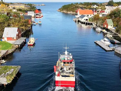 a red and white boat is docked in a river at 8 person holiday home in averøy-By Traum in Averoy
