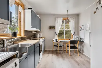 a kitchen with a sink and a table with chairs at Tysso Apartment in Tveit