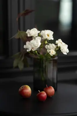 a vase with white flowers and three apples on a table at Luxurious 5-Bedroom Mountain Chalet with Sauna, Panoramic Views, and Two Full Bathrooms in Stranda