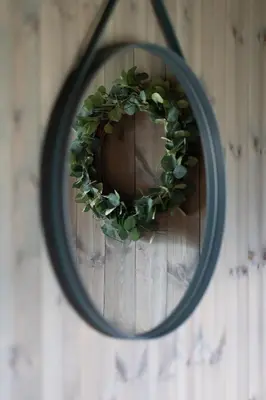 a mirror with a green wreath on a wall at Luxurious 5-Bedroom Mountain Chalet with Sauna, Panoramic Views, and Two Full Bathrooms in Stranda